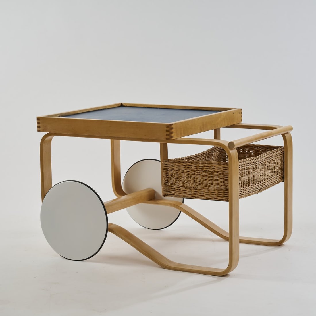 Alvar Aalto, Serving trolley '100/900', 1937: H. 58 x 90 x 66 cm. Made by Artek, Helsinki. Birch wood, birch plywood, partially painted white, blue linoleum, wicker. Literature: Cf. Kellein (ed.), Alvar & Aino Aalto. Design, Bielefeld 2005,