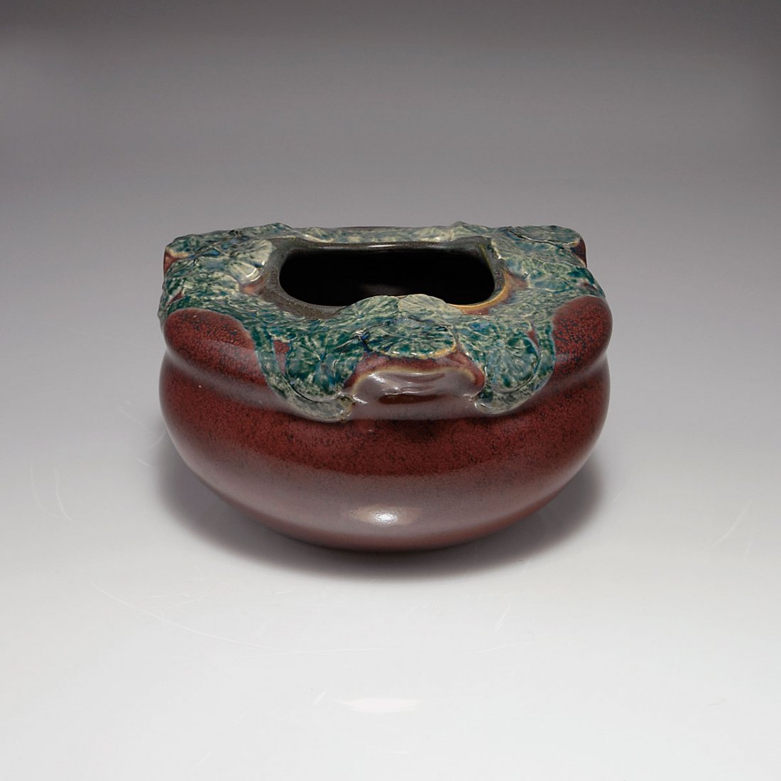 Vase, c1898: Theodor Schmuz-Baudiss. Vase, c1898. H. 10 cm; D. 17.5 cm. Earthenware, glazed dark red and green, reliefed pattern with leaves. Marked: 12.31 STB, 9713 (...).