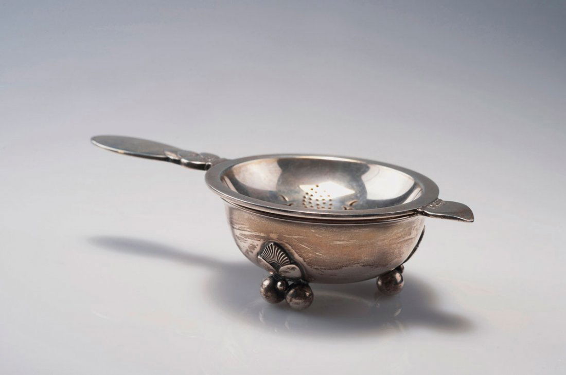 'Cactus' tea sieve with bowl, 1930: Georg Jensen, Copenhagen. 'Cactus' tea sieve with bowl, 1930. L. 13.5 cm; bowl, H. 2.4 cm; D. 6.5 cm. Designed by Gundorph Albertus. Made between 1933-44. Silver. Marked: GJ, STERLING DENMARK, 925, bo