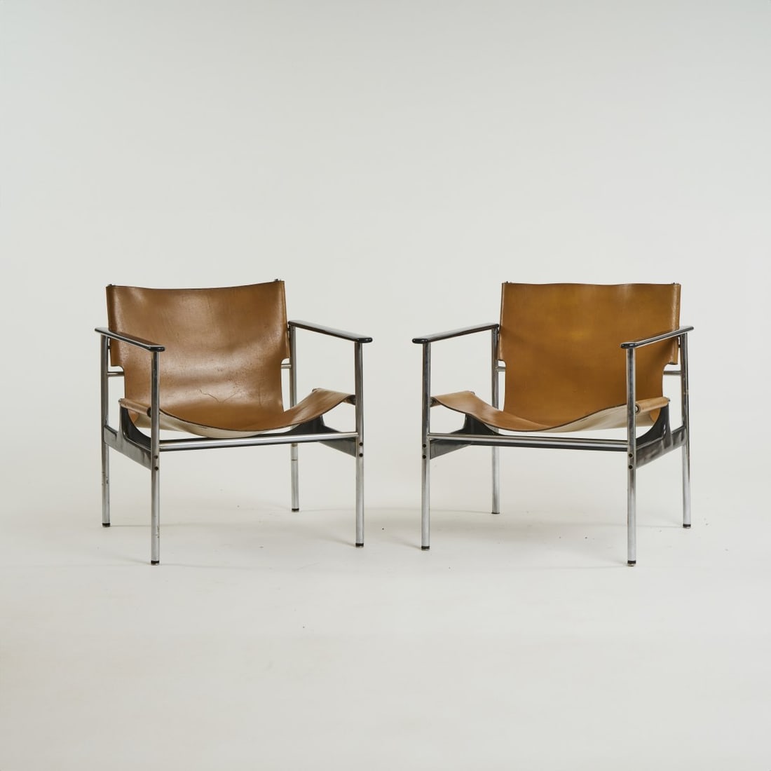 Charles Pollock, Two '657' - 'Sling' armchairs, 1960 (design): H. 69 x 63 x 65 cm. Knoll International, New York. Chrome-plated tubular metal, wood, varnished black, brown leather.