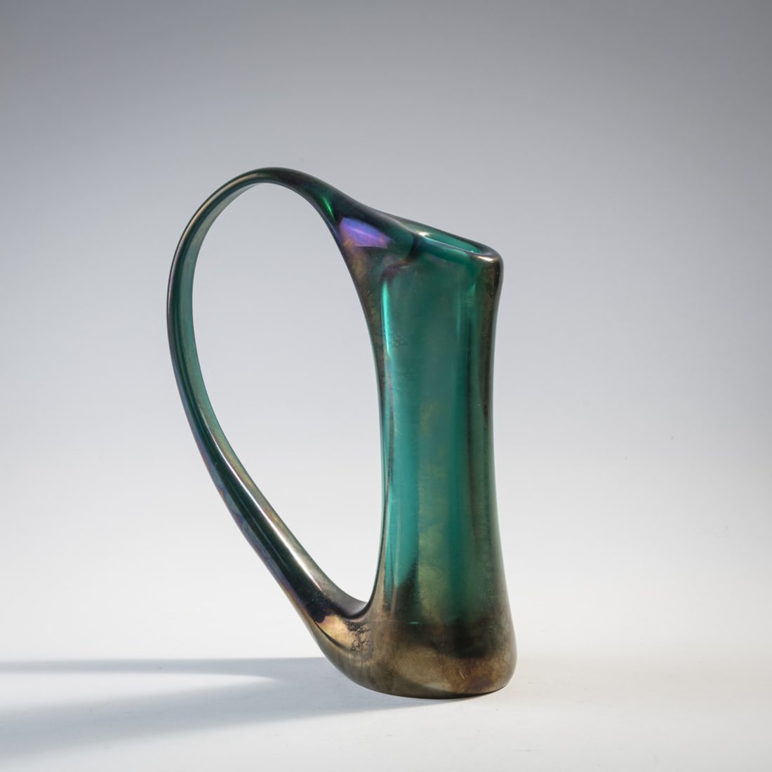 Giorgio Ferro, 'Anse volante' vase, c. 1952: Ring-like body, heavily flattened on both sides, on an oval base. H. 26.5 cm. Execution: A.Ve.M. Thick-walled glass, dark green, iridescent.