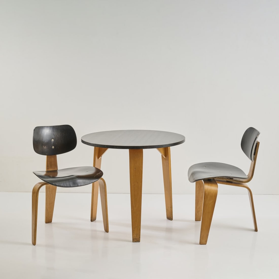 Egon Eiermann, Two 'SE 42' chairs and '254' table, 1949/52: Chair: H. 74 x 54 x 50,5 cm, table: H. 67 cm; Ø 75 cm.Wilde & Spieth, Esslingen. Beech plywood, painted red, rubber and wooden buffers. Literature: Exh. cat. Egon Eiermann. Die Möbel,