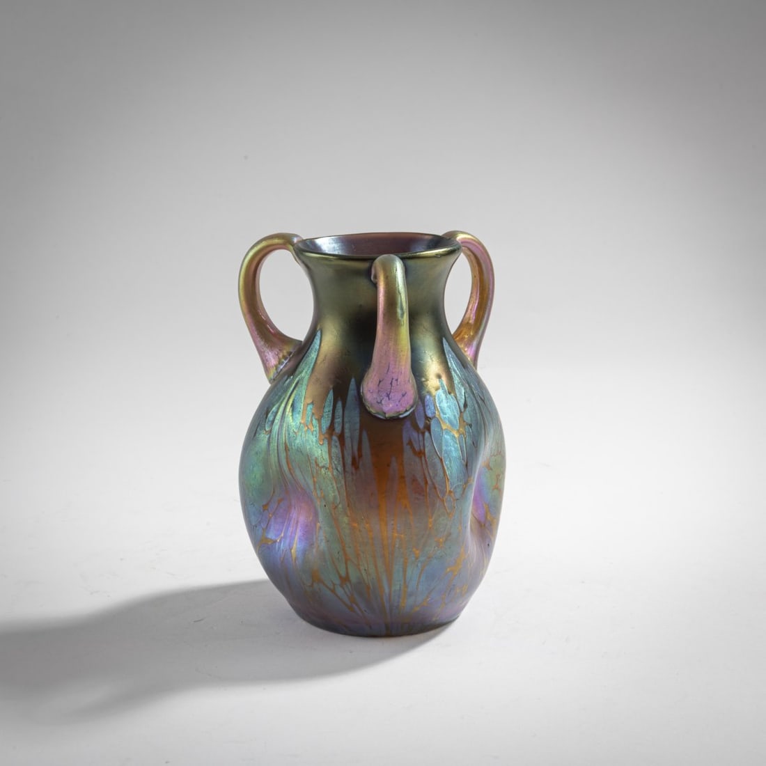 Loetz, Klastersky Mlyn, Vase with handles 'Medici', 1902: H. 12.4 cm. Cased glass, colorless, 'marron' gradient, fused silver-yellow crumbs 'Medici' decoration, strong petrol and bronze matt luster.