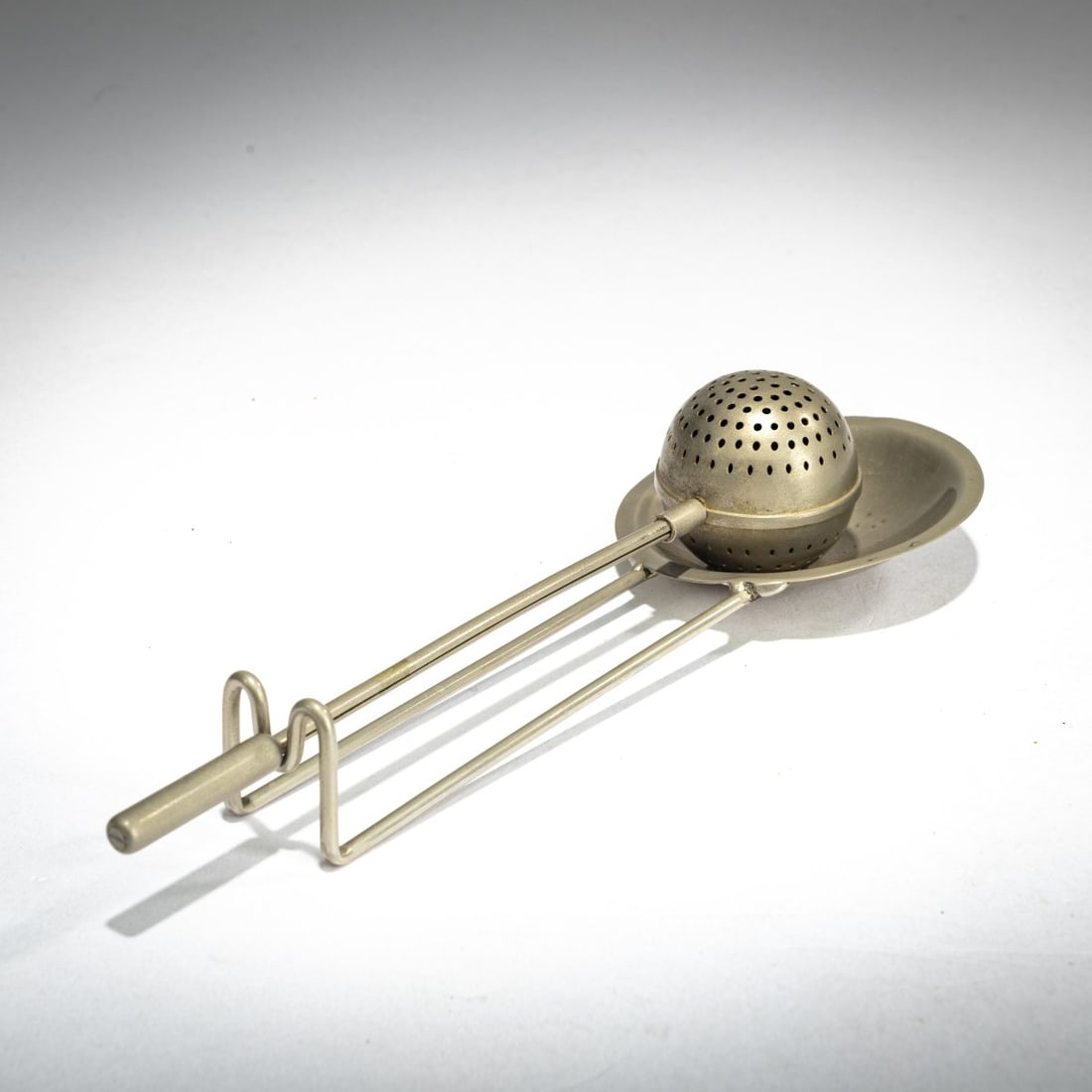Josef Knau, Tea egg with holder, c. 1924: L. 17 cm (total). Bauhaus, Dessau (probably). Brass rods, white metal sheet, nickel-plated. Literature: Provenance: From the collection of the daughter of a former Bauhaus alumni and Burg Giebichenst