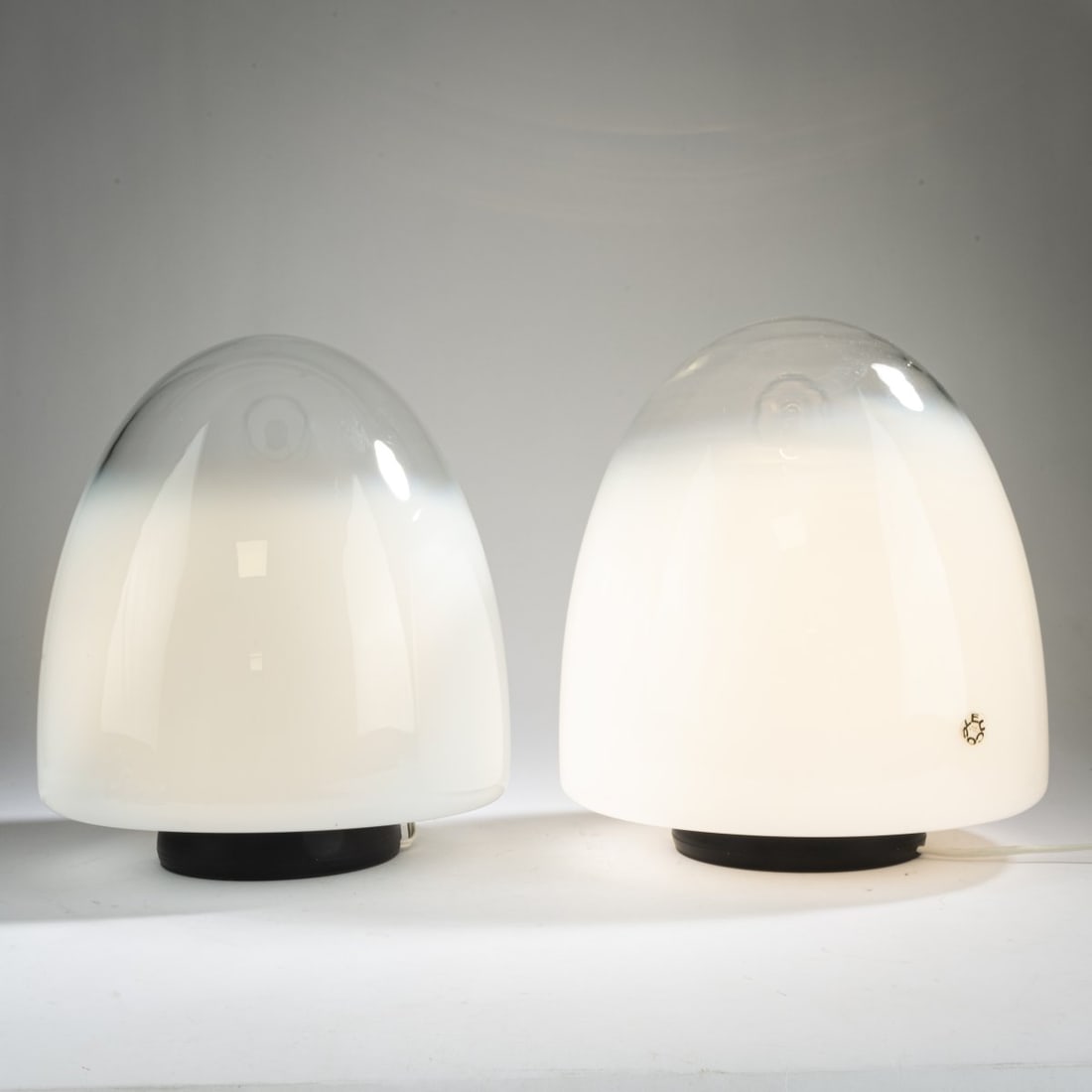 Giusto Toso , Two table lights 'Ebe', c. 1970 (design): <p>H. 34.5-36 cm, &Oslash; 29-32 cm. <br />Leucos, Milan. <br />Glass, colorless, opal white gradient, white plastic or white painted metal sheet. <br />Marked: manufacture