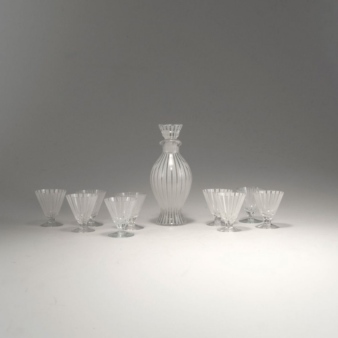 Bengt Orup. Seven sherry glasses and 'Strikt' carafe, 1: Bengt Orup. Seven sherry glasses and 'Strikt' carafe, 1950s. H. 23.9 cm; H. 8-8.2 cm. Made by Johanfors Glasbruk. Clear glass, white and grey enamel. Marked: 8.