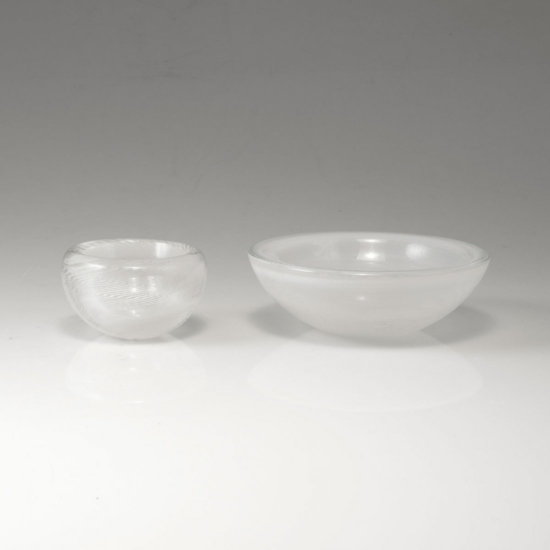 Carlo Scarpa. Two 'Mezza filigrana' bowls, c1934. H. 4.: Carlo Scarpa. Two 'Mezza filigrana' bowls, c1934. H. 4.5-4.9 cm. Made by Venini & C. Cased glass, clear, included opaque white spiral. Smaller bowl marked: venini murano (acid stamp).