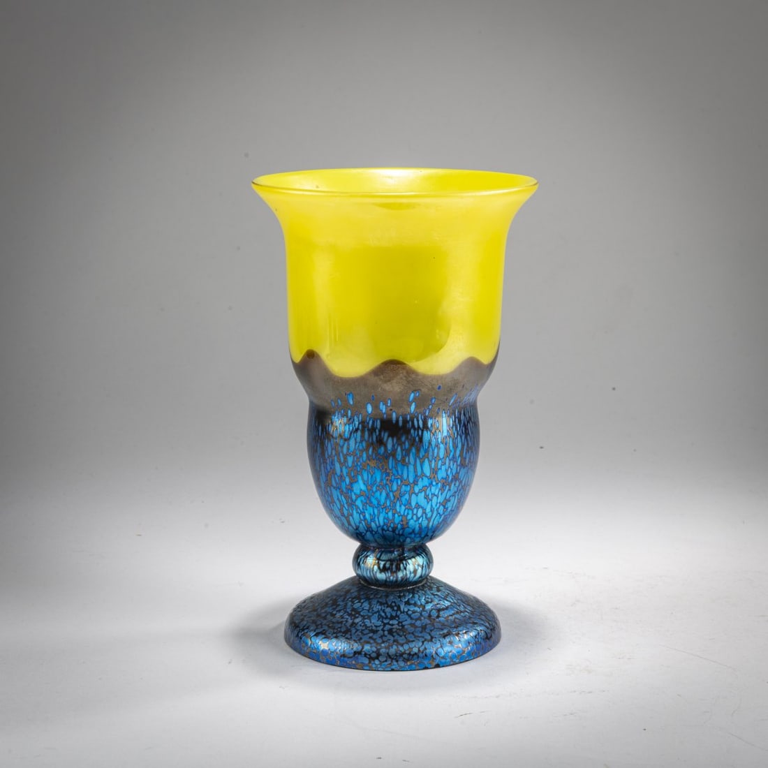 Loetz, Klastersky Mlyn, Footed vase, c. 1925: <p>H. 25.5 cm. Cased glass, colorless, lemon yellow, and violet. Blue crushed glass with a matte petrol and pearlescent luster. Execution 226, lemon yellow. </p>