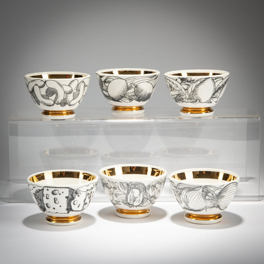 Piero Fornasetti, Six appetizer bowls, 1960s (design): <p>H. 5.2 cm, &Oslash; 7.8 cm.<br />Fornasetti, Milan. <br />White porcelain, glazed, with black and white lithographic decoration and gold. <br />Marked: brush mark.</p