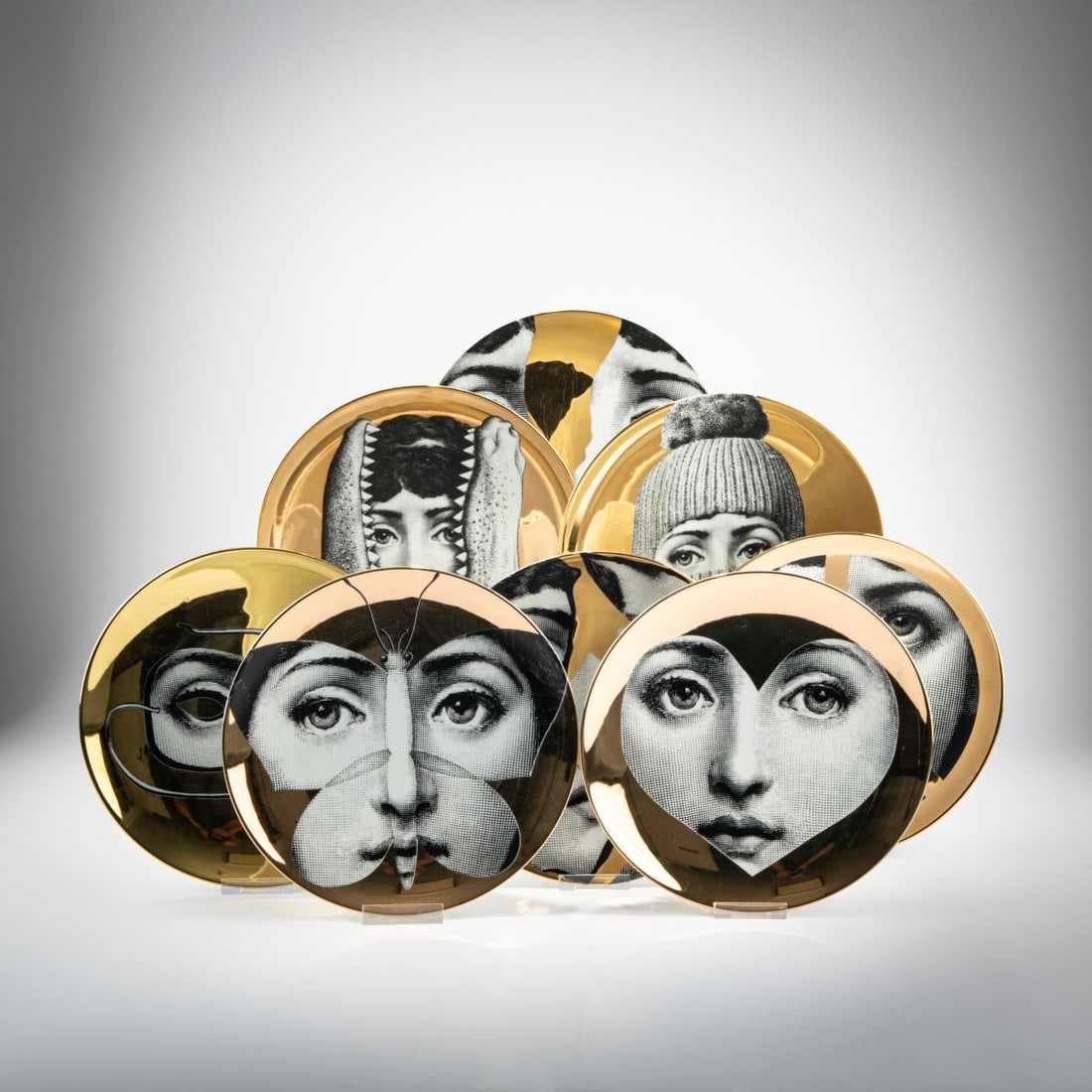 Piero Fornasetti, Eight plates from the series 'Tema e Variazione', 1950s to 2000s (design): <p>H. 3 cm, &Oslash; 26.3 cm.<br />Fornasetti, Milan, 2000s.<br />White porcelain, glazed, black and white lithographic decoration with gold. <br />Marked: brush and maker'