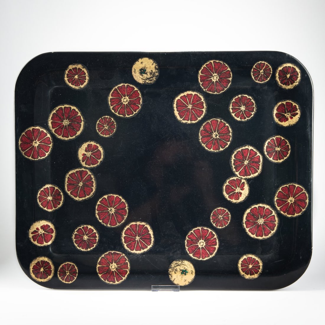 Piero Fornasetti, Tray 'Fette d'arancia' , 1950s: <p>46 x 58 cm. <br />Fornasetti, Milan. <br />Sheet metal, painted black, red, and green, with gold. <br />Marked: brush mark.</p><hr><p>Literature:</p>