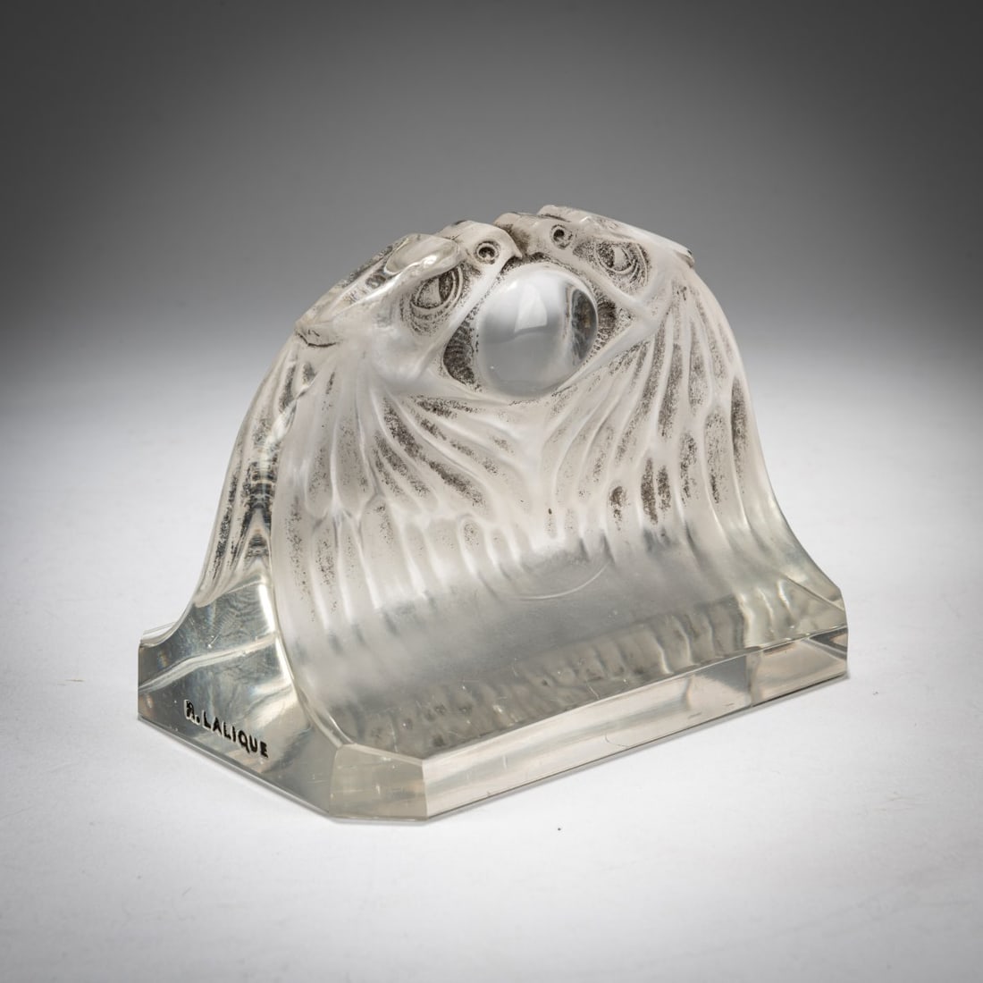 René Lalique, Paperweight 'Deux Aigles', 1914: <p>H. 7.7 x 10.4 x 7 cm. Execution: Lalique, Wingen-sur-Moder. Pressed glass, colorless, with a gray patinated finish. Marked on the side: R.LALIQUE (embossed and rubbed in black). </p><