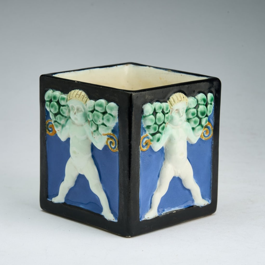 Michael Powolny, Flower pot with four putti reliefs, 1907: <p>H. 9.2 cm. Execution: Wiener Keramik. Earthenware, relief-decorated, polychrome glaze. Bottom marked: Wiener Keramik signet, artist's signet PM, 107 (stamped), /a (black, handwritten).</p&