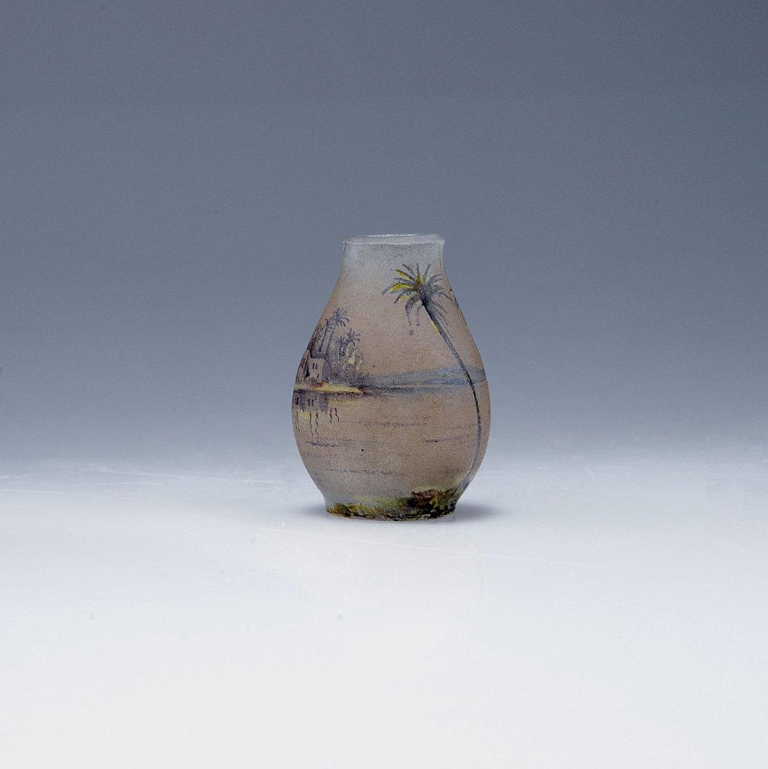 Miniature vase 'Nil', 1905: Daum Freres, Nancy. Miniature 'Nil' vase, 1905. H. 3.6 cm. Cased glass, clear, milky opalescent powder inclusions. Etched and enamelled. Shores of the Nile river with palmtrees and temples. Signed: DA