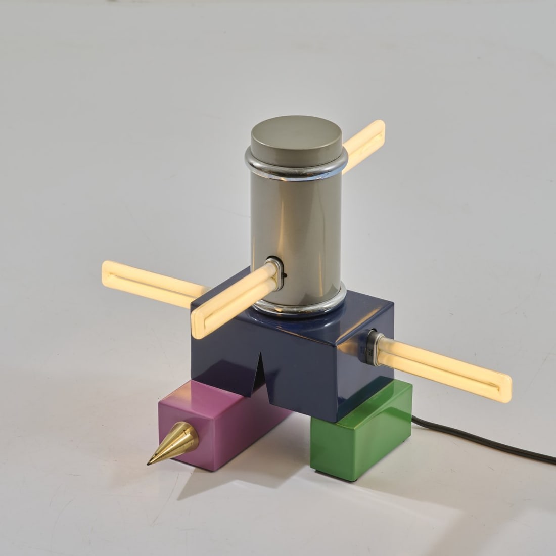 Peter Shire, Table light 'Laurel', 1985 (design): <p>H. 29.5 cm. <br />Memphis, Milan. <br />Sheet steel, painted dark blue, violet, green, gold, and metallic gray. <br />Marked: Manufacturer's label MEMPHIS MILANO, PETER SHIR