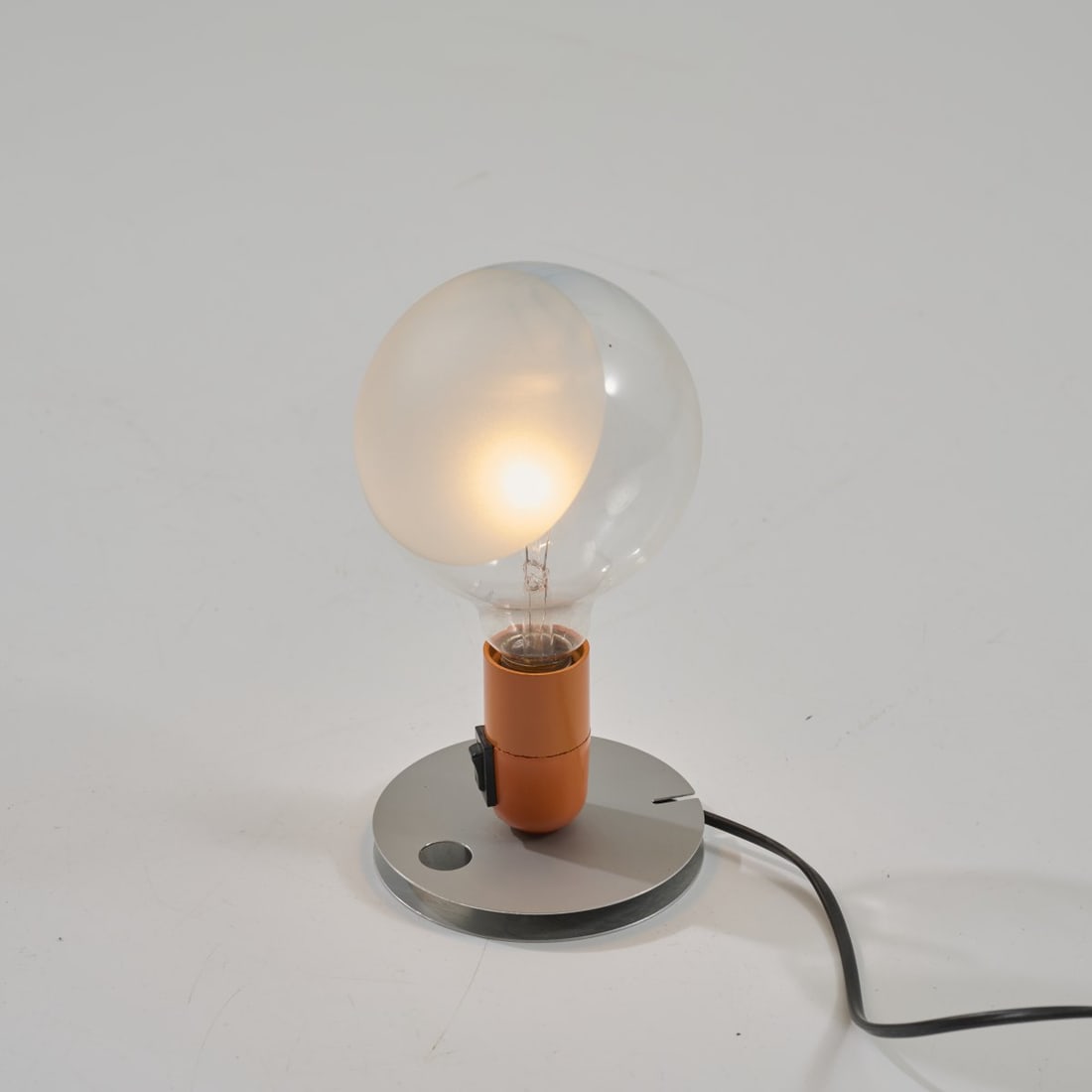 Achille Castiglioni, Table light 'Lampadina', 1972 (design): <p>H. 25 cm. <br />Flos, Brescia. <br />Aluminum sheet, metal sheet, orange, colorless, semi-frosted light bulb. <br />Marked: Manufacturer and designer's details.</p><