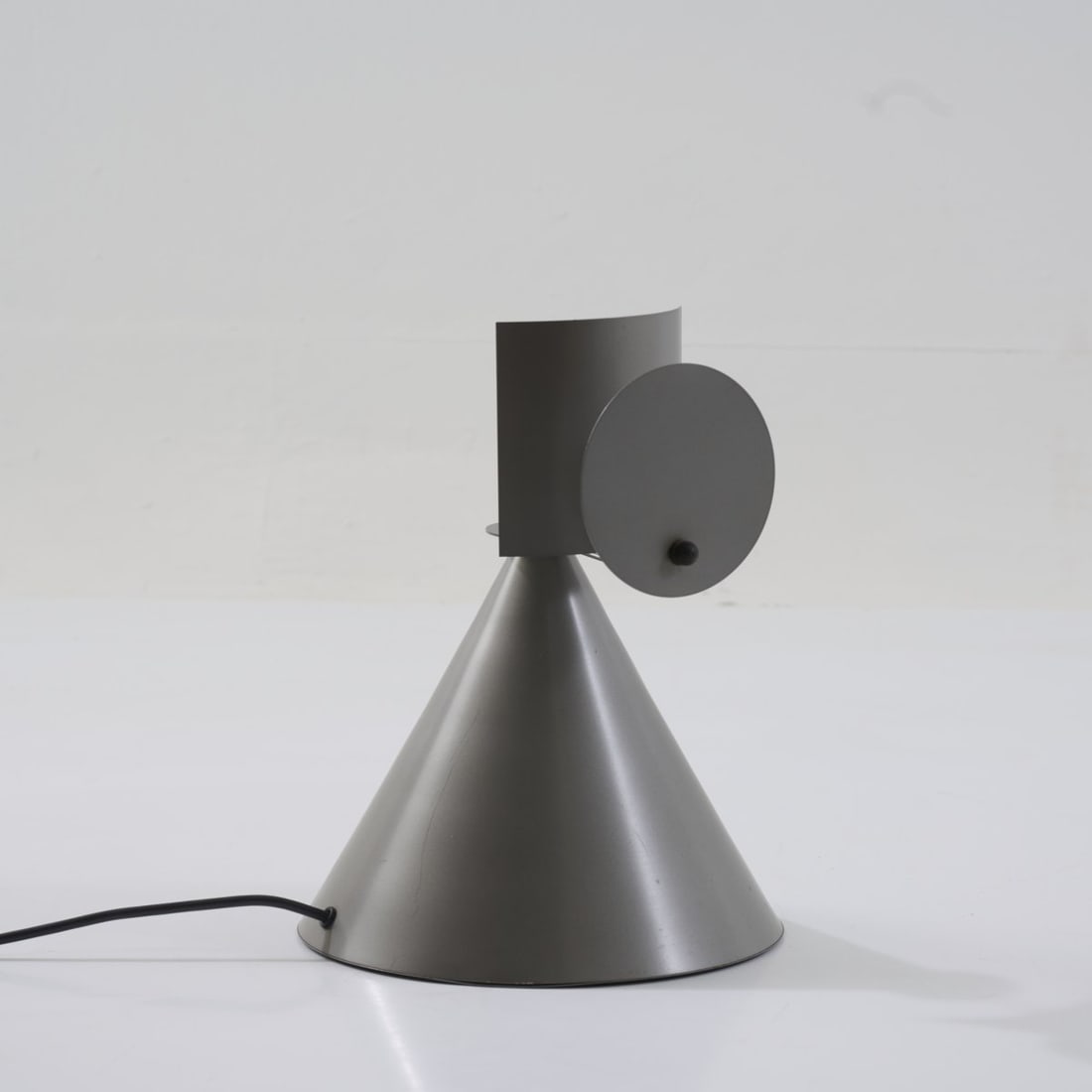 Marco Zanuso Jr., Table light 'Eco', 1982 (design): <p>H. 34 cm. <br />Oceano Oltreluce, Milan. <br />Aluminum sheet and brass, lacquered silver-gray, black rubber. <br />Marked: Manufacturer's label</p><hr><p>