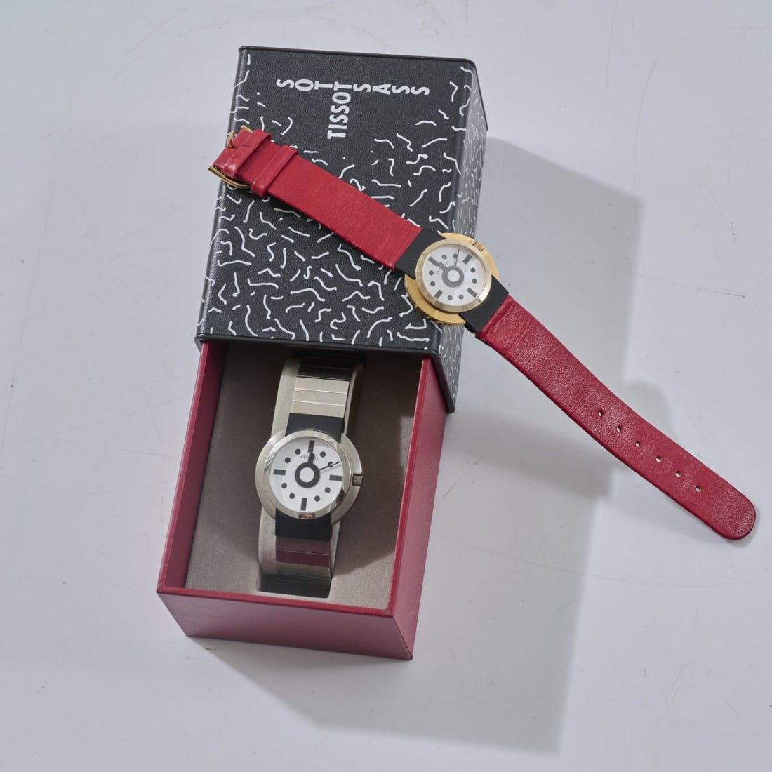Ettore Sottsass, Two wristwatches, 1980 (design): <p>Bezel: &Oslash; 32 mm; L. 23.1 cm. <br />Tissot SA, Le Locle, 1988. <br />18K yellow gold, stainless steel, glass, red leather strap. <br />Marked: &copy; Facsimile