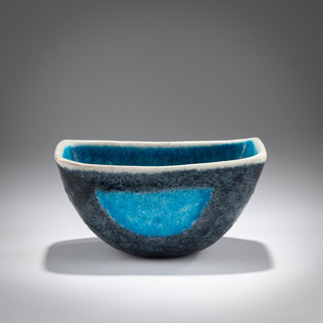 Guido Gambone , Small bowl, c. 1955: <p>H. 10.2 x 19.5 x 10 cm.<br />Faience, glazed in blue and anthracite gray on white. <br />Marked: Donkey, GAMBONE ITALY. </p>