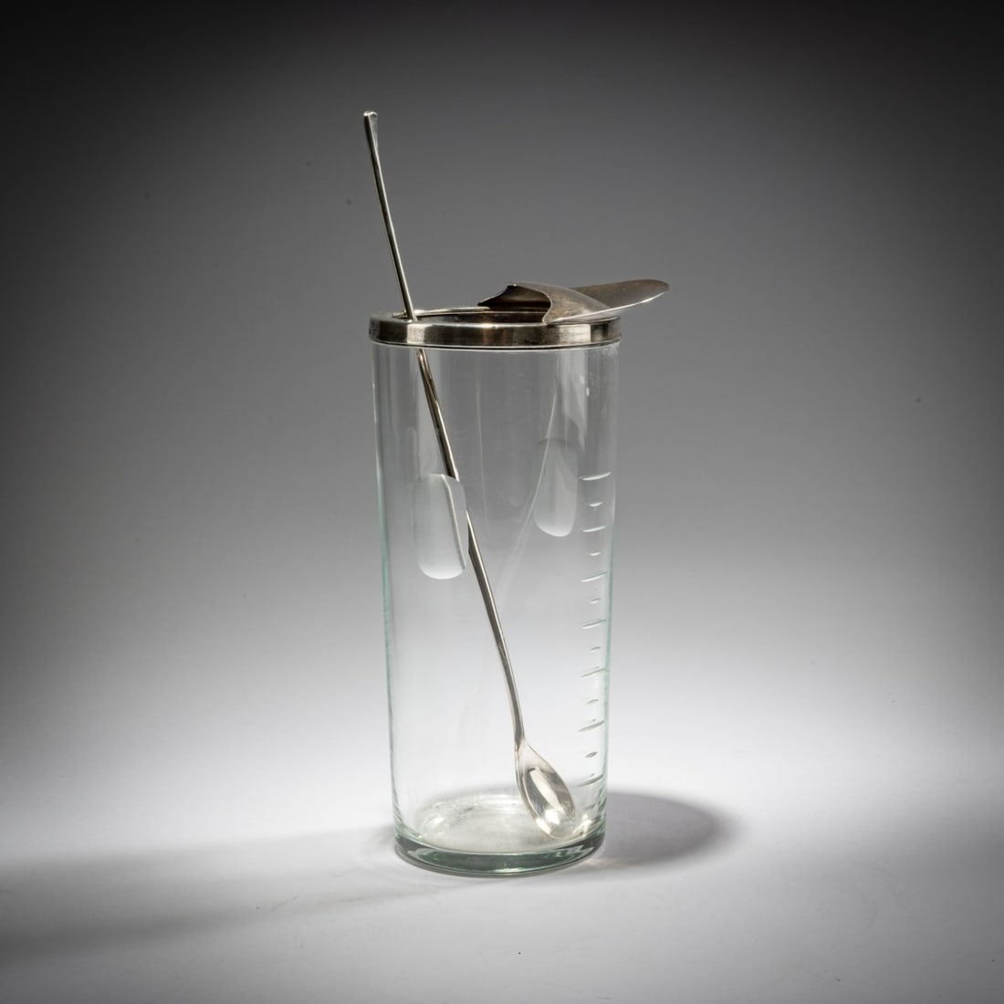 Anton Michelsen, Cocktail shaker with bar spoon, 1960s: <p>H. 22 cm; Spoon: L. 29.9 cm. <br />Anton Michelsen, Copenhagen. <br />Colorless glass with cut scale markings, silver. <br />Marked: Manufacturer's mark A. MICHELSEN COPENHA