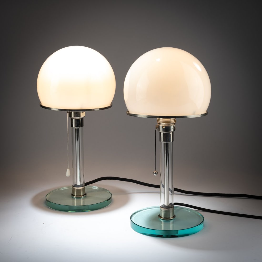 Wilhelm Wagenfeld, Two table lights 'WG 24', 1924 (design): <p>H. 36.5 cm, &Oslash; 18 cm. <br />Tecnolumen, Bremen. <br />Metal tube, chrome-plated sheet metal, glass shaft and base, white glass shade. <br />Marked: TECNOLUMEN