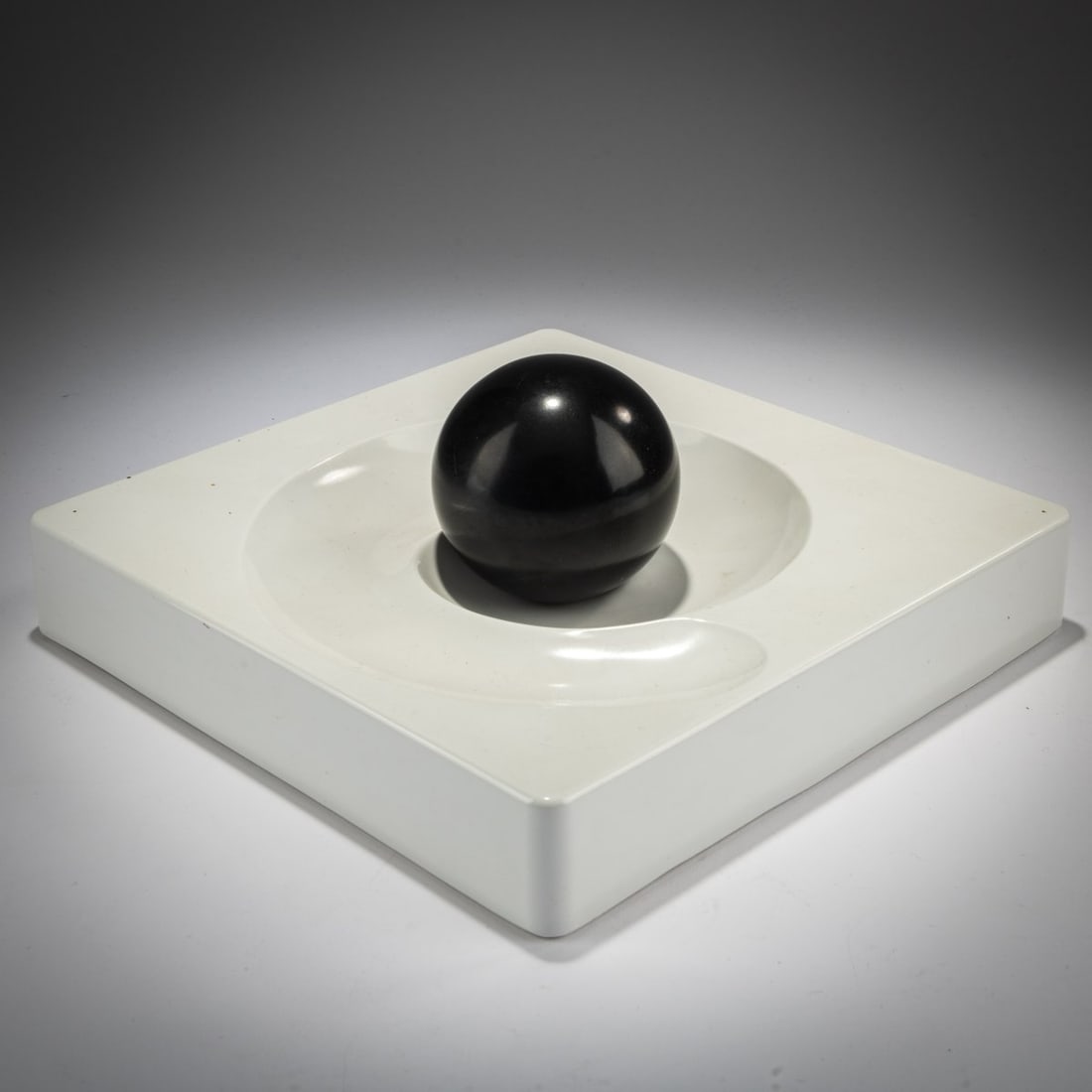Eleonore Peduzzi Riva, Ashtray 'Spiros' with ember snuffer, 1969 (design): <p>H. 3.7 x 21.7 x 21.7 cm; Sphere: &Oslash; 6.5 cm. <br />Artemide, Milan. <br />White and black melamine. <br />Marked: Manufacturer's mark (embossed).