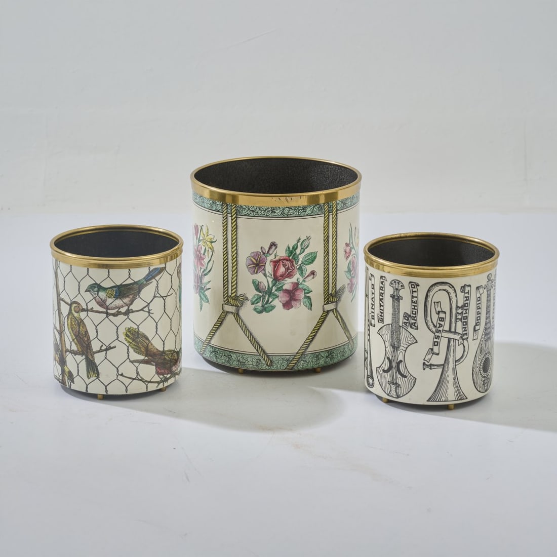 Piero Fornasetti, Three wastepaper baskets 'Uccelli nella gabbia', 'Tamburo con fiori' und: <p>H. 21.5&ndash;228.5 cm, &Oslash; 19.5&ndash;26 cm. <br />Fornasetti, Milan. <br />Sheet metal, lacquered black, polychrome lithographic decoration. <br