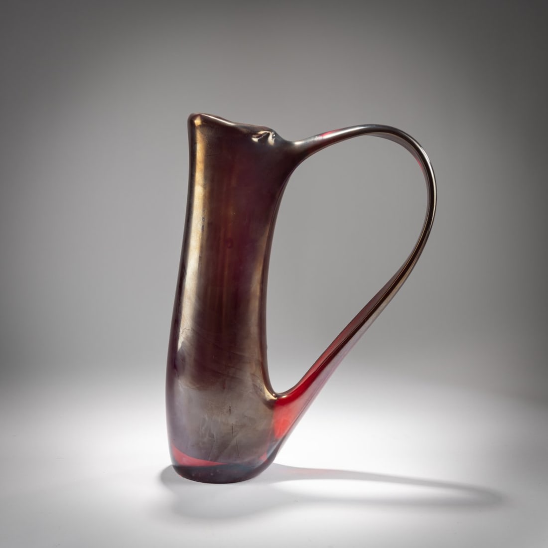 Giorgio Ferro, Vase 'Anse volante', c. 1952: <p>H. 35 cm. Execution: A.Ve.M. Thick-walled, red glass, petrol iridescent. </p><hr><p>Literature:</p><p>Cf. Marc Heiremans, AVEM, Stuttgart 2020, p. 204.</p>