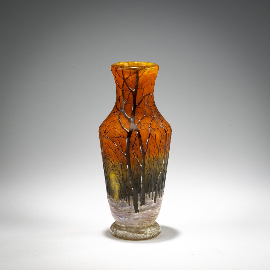 Daum Frères, Nancy, Small 'Crépuscule neige' or 'Paysage d'hiver' vase, c. 1902: <p>H. 14.5 cm. Overlaid glass, colorless, with yellow, orange, and dark brown powder inclusions. Etched decoration, heightened with black solder and enameled white, depicting a winter forest lan