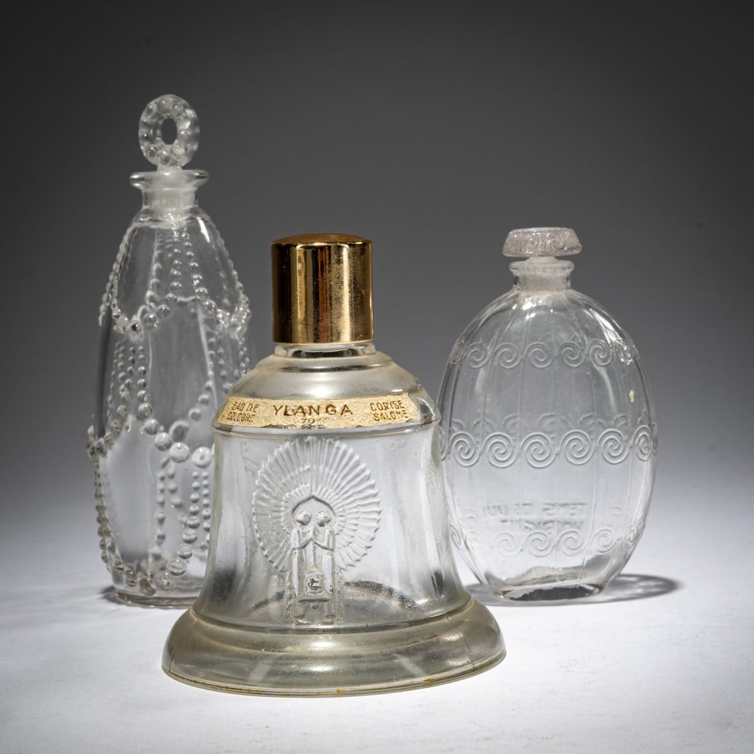 René Lalique, Three bottles of 'Temps de Lilas', 1920 for Houbigant, 'Palerme' 1926 and: <p>'Temps de Lilas': H. 8.7 cm. Execution: Ren&eacute; Lalique, Wingen-sur-Moder. Pressed glass, colorless. Signed: LE TEMPES DES LILAS HOUBIGANT, FRANCE (impressed), 282 (engraved). <br