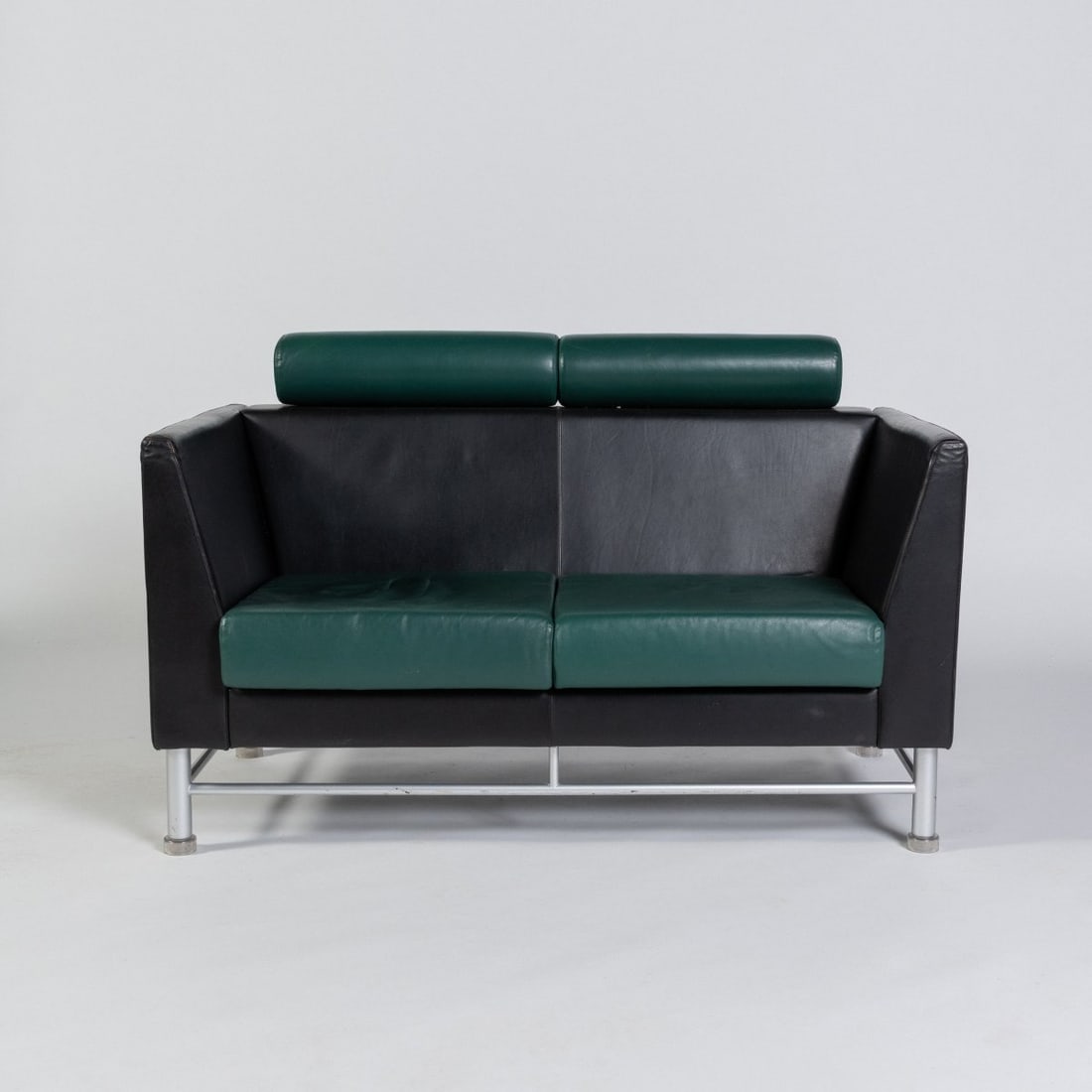 Ettore Sottsass, Two-seater sofa from the 'Eastside Collection', 1982 (design): <p>H. 70 x 137 x 75 cm. <br />Knoll International, New York. <br />Satin-finished metal tube, transparent plastic feet, wooden frame, foam padding, black and green leather. <br /&