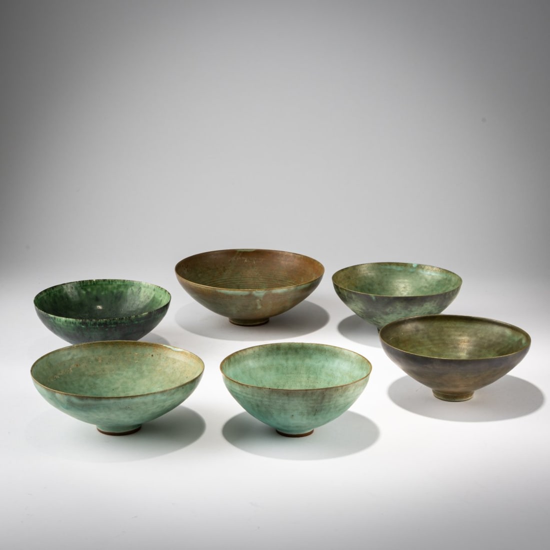 Görge Hohlt, Six bowls, c. 1969 (design): <p>H. 5.8&ndash;6.1 cm, &Oslash; 13.5&ndash;16.7 cm. <br />Stoneware, with celadon green or copper oxide glazes. <br />Marked: Workshop mark of a cat, GH (5x) (stamped).&