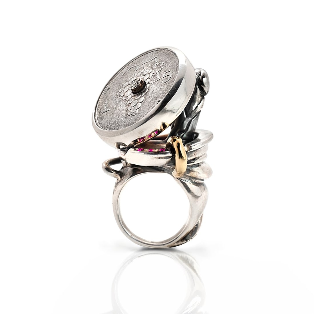 Faust Cardinali (1961 Paris - lives and works between Paris and Tuscany), Unikat-Ring 'Schèi: <p>Sterling silver, yellow gold, 5 lire coin, diamond, three rubies. <br />49.65 grams. Height 50 mm, ring size 56.5. <br />Stamped: 925, workshop mark.</p>