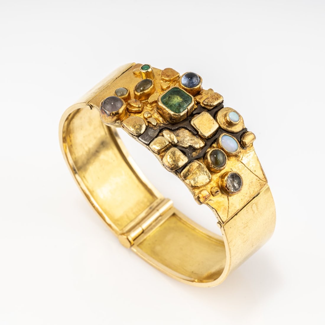 Hermann Jünger (1928 Hanau - 2005 Poering near Munich), Bangle, 1968: <p>Fine gold, 18k yellow gold (750), silver, emerald-cut tourmaline, various gemstone cabochons including opal, moonstone, rock crystal, and chrysoberyl. Pin clasp. <br />49.91 grams. &