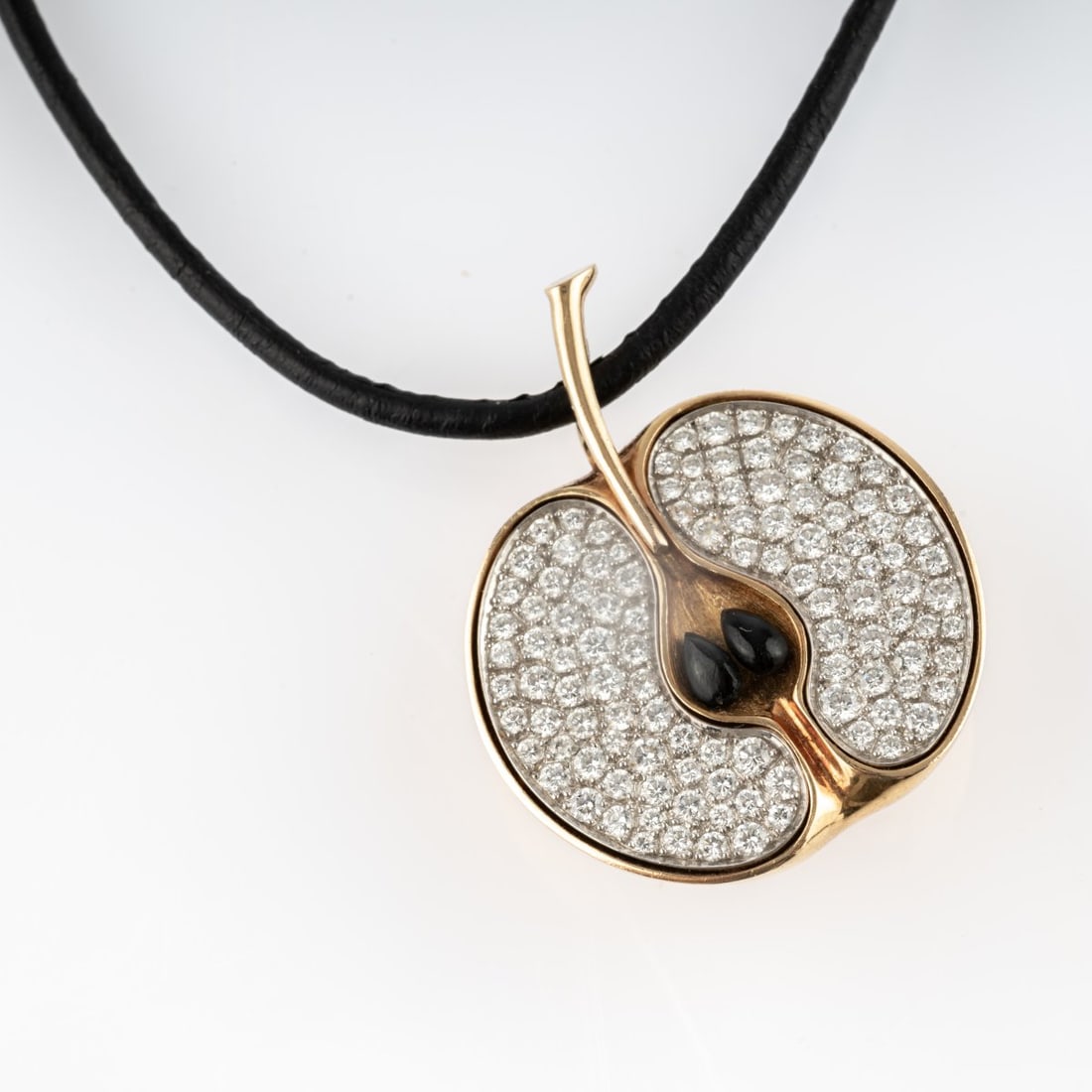 Paul Binder, Zurich, Pendant 'Apfel': <p>18k yellow gold (750), pav&eacute;-set diamonds (approx. 2.3 ct., calculated weight), onyx apple seeds, leather strap. <br />21.46 grams. 40 x 32 mm. <br />Clasp stamped: