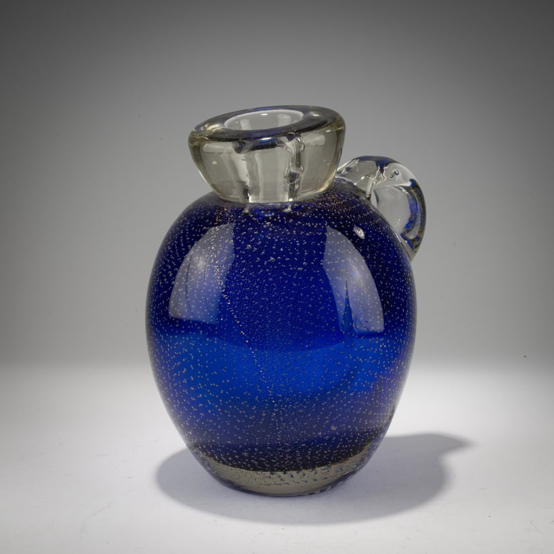 Flavio Poli, 'A bollicine oro' jug, c. 1941: <p>H. 23.5 cm. Execution: Seguso Vetri d'Arte. Cased glass, colorless and blue, with regularly punctured air bubbles and finely burst gold foil.</p>