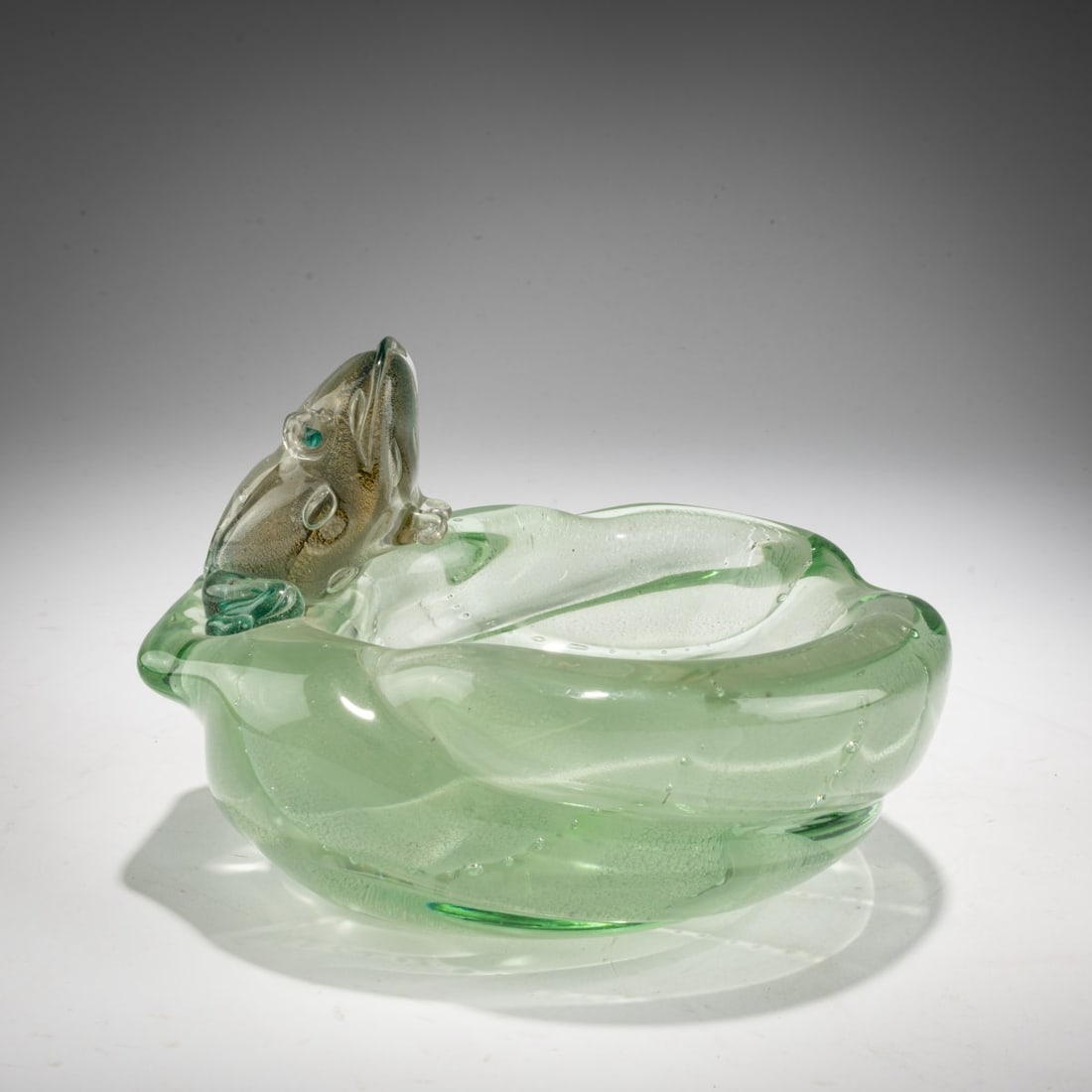 Luigi Scarpa Groce, Bowl with a frog, c. 1942: <p>H. 11.7 cm; &Oslash; approx. 15 cm. Execution: V.A.M.S.A. Thick-walled glass, colorless and green, partly heavily bubbled, with embedded air bubbles and finely burst gold leaf. </p>