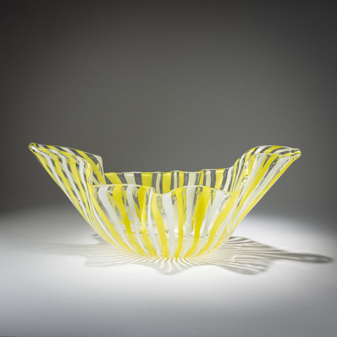 Fulvio Bianconi, 'Fazzoletto a canne' vase, c. 1950: <p>Model No. 4240. H. 20 cm; L. 48.5 cm. Execution: Venini. Cased glass, colorless with fused bands in white and lemon yellow. Marked: venini murano ITALIA (acid stamp). </p><hr><