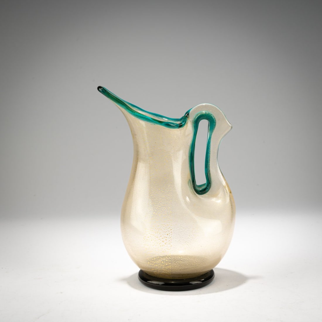 Ercole Barovier, Small 'Eugeneo' jug 1951: <p>H. 17.8 cm. Execution: Barovier &amp; Toso, Murano. Glass, colorless, with finely burst gold foil; base, rim, and handle loops in turquoise glass.</p>