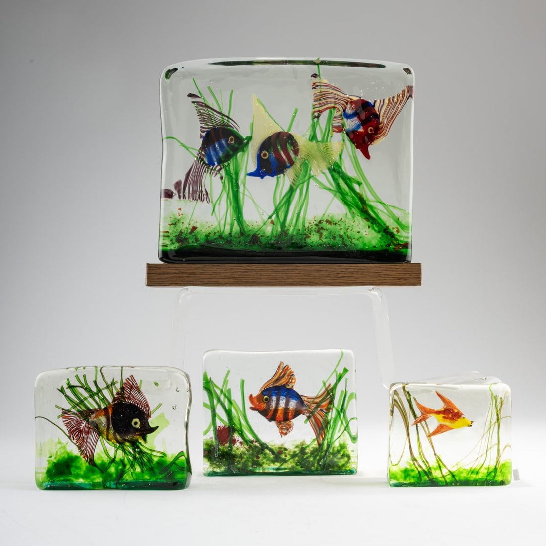 Cenedese, Four Aquariums, c. 1960: <p>H. 10 cm; 11.5 x 3.5 cm or H. 12 cm; 15 x 4.5 cm or H. 13 cm; 16 x 4 cm and H. 20 cm; 25.5 x 5.5 cm (without base). Colorless glass block with polychrome inclusions. One piece with a wooden