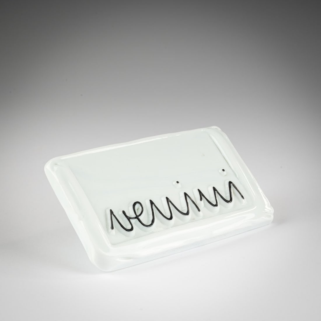 Venini, Advertising sign 'Venini', 1960s: <p>9 x 16 cm. Opaque white and black enamelled glass; metal hook, white lacquered.</p>
