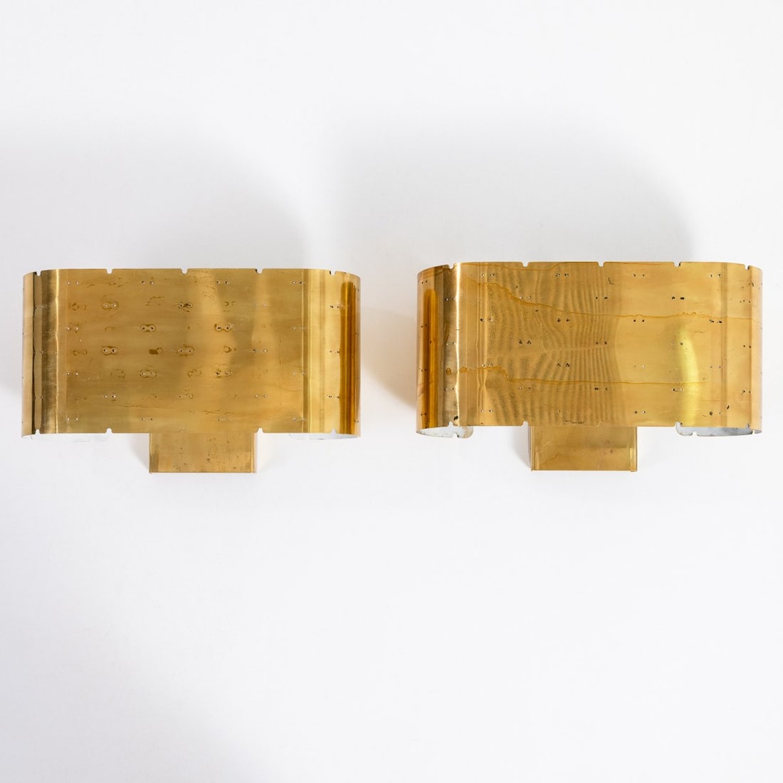 Paavo Tynell, Two '9460' wall lights, 1940s (design): <p>H. 17.5 x 31.5 x 13.5 cm.<br />Idman Oy, Helsinki.<br />Perforated brass sheet, partially painted white.<br />Marked: Manufacturer's