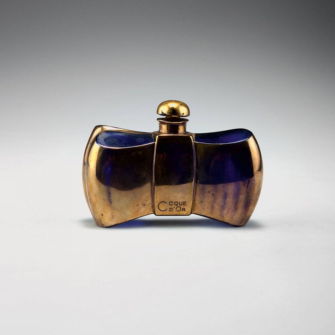 Cristallerie de Baccarat. 'Coque d'or' flacon for: Cristallerie de Baccarat. 'Coque d'or' flacon for Guerlain, 1937. H. 7.8 cm. Moulded blue glass, part gilded. Inscribed: COQUE D'OR, GUERLAIN. Marked: guerlain, maker's mark, 165.