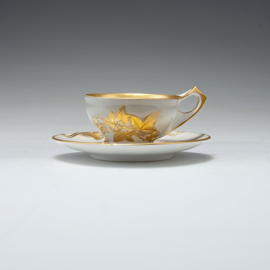Mocha cup and saucer: KPM Berlin. Mocha cup and saucer, 1902. H. 3.8 cm. Porcelain, white, glazed, grey overglaze, vine pattern, relief gold. Marked: Maker's mark, painter shop, gg, N, datemark B.