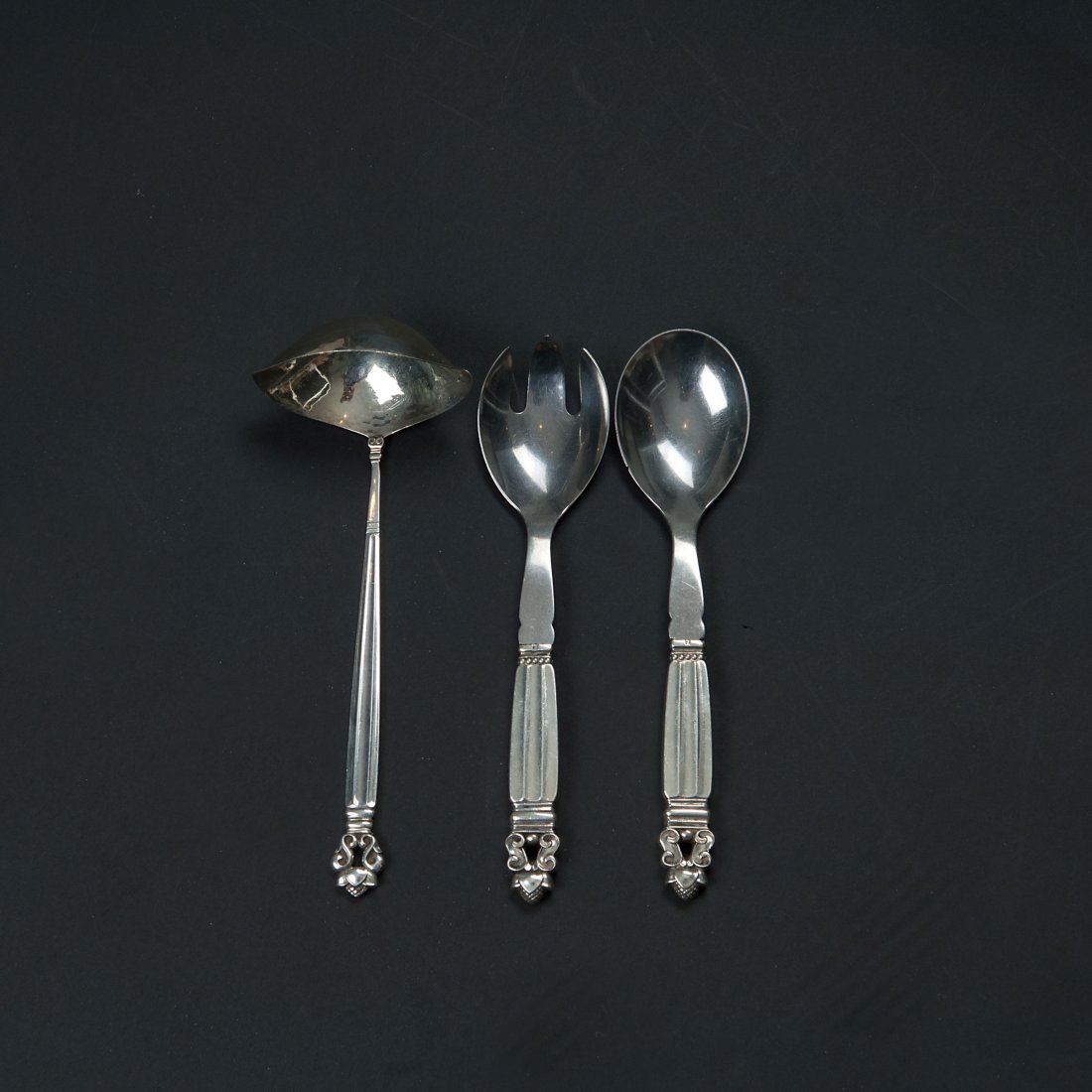 'Konge - Acorn' salad cutlery and gravy ladle: Johan Rohde. 'Konge - Acorn' salad cutlery and sauce ladle, 1915. Three pieces. Salad cutlery, L. 20 cm; sauce ladle, L. 20 cm. Made by Georg Jensen, Copenhagen, 1915-27 and 1933-44. Silver, stainless