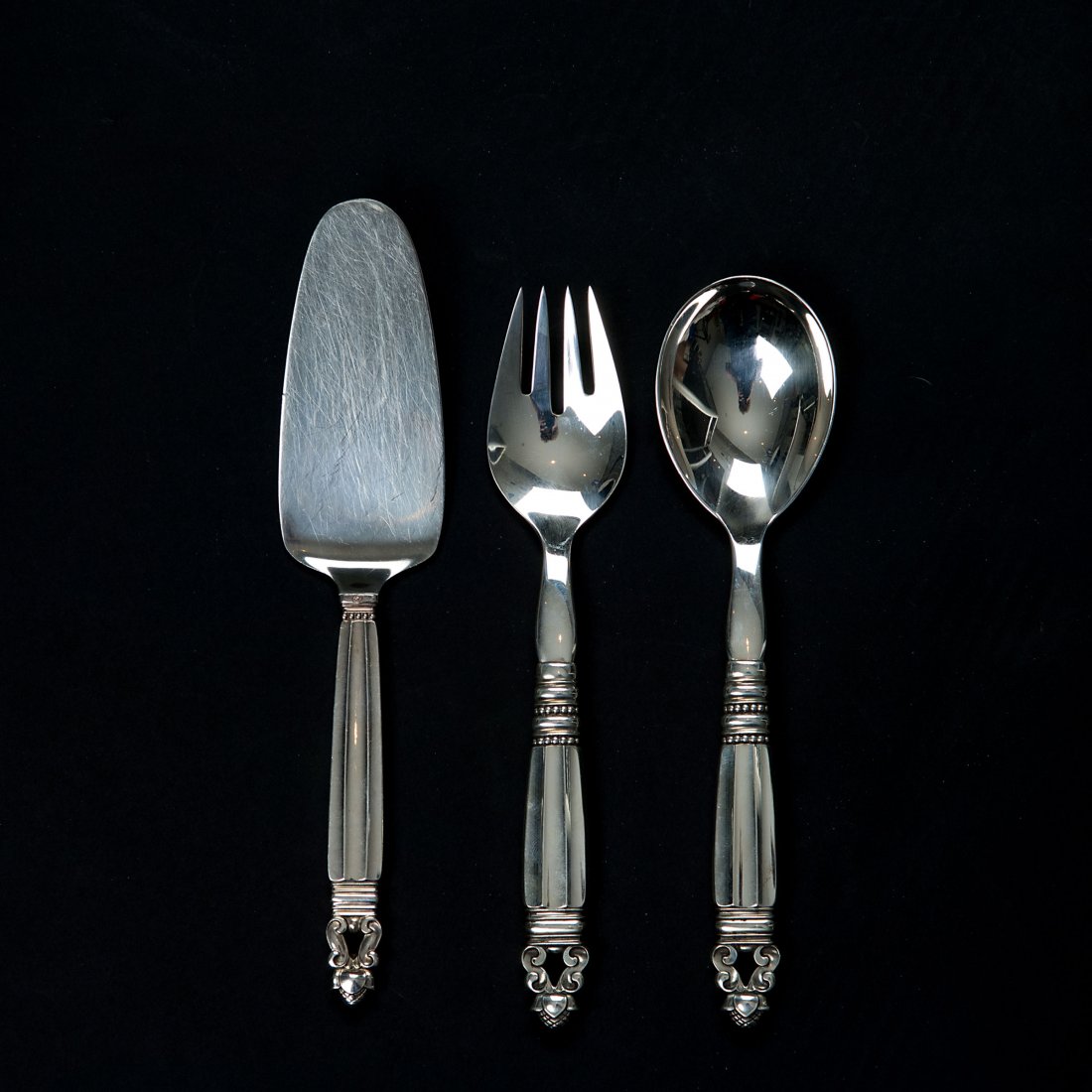 'Konge - Acorn' serving cutlery and cake server: Johan Rohde. 'Konge - Acorn' serving pieces and cake server, 1915. Three pieces. Serving spoon, L. 21.5 cm; serving fork, L. 21.5 cm; cake server, L. 23 cm. Made by Georg Jensen, Copenhagen, 1915-27 a