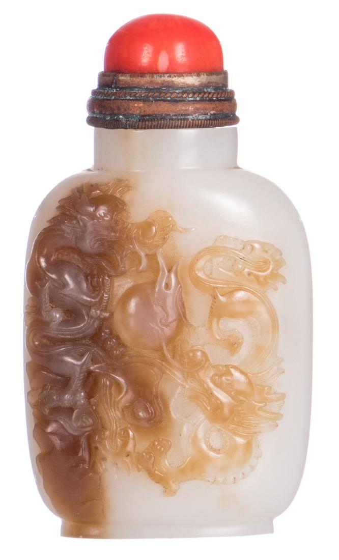 A Chinese light celadon coloured and brown jadeÂ snuff: A Chinese light celadon coloured and brown jadeÂ snuff bottle, depicting two Chilongs playing with a flaming pearl, the cap of blood coral, H 7,5 cm