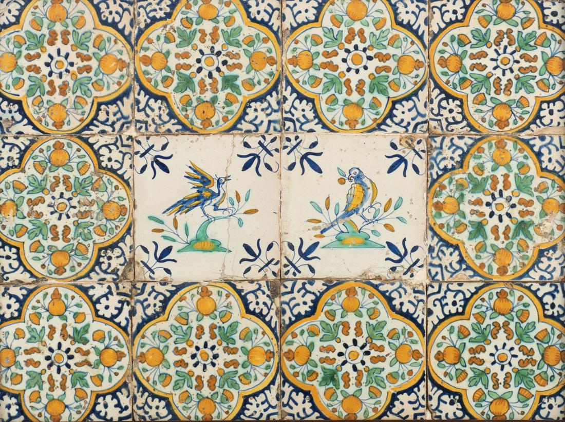 A polychrome decorated Dutch Delftware tile panel,: A polychrome decorated Dutch Delftware tile panel, consisting of 12 tiles, the central two depicting birds, the others decorated with 'oranjeappels in een kwart vierpas' (orange apples in a quatrefoil