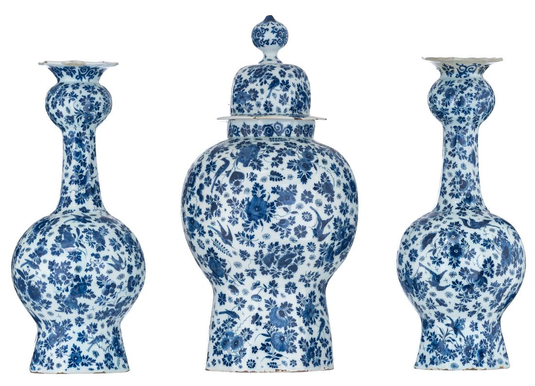 A three-piece blue and white Delftware garniture,: A three-piece blue and white Delftware garniture, horror vacuum decorated with birds in a floral setting, consisting of one covered vase and two garlic bottle vases, 18thC, H 42 - 50 cm