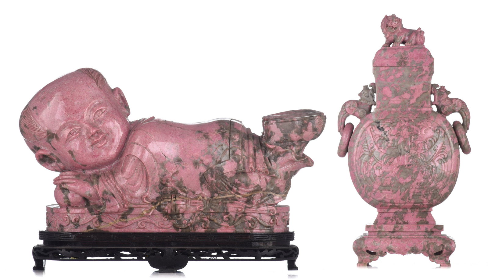 A Chinese sculpted rhodonite ornament in the shape of: A Chinese sculpted rhodonite ornament in the shape of a neck pillow, H 22 - L 38 cm - added a rhodonite carving of a vase and cover, H 42 - W 25 cm A Chinese sculpted rhodonite ornament in the shape o